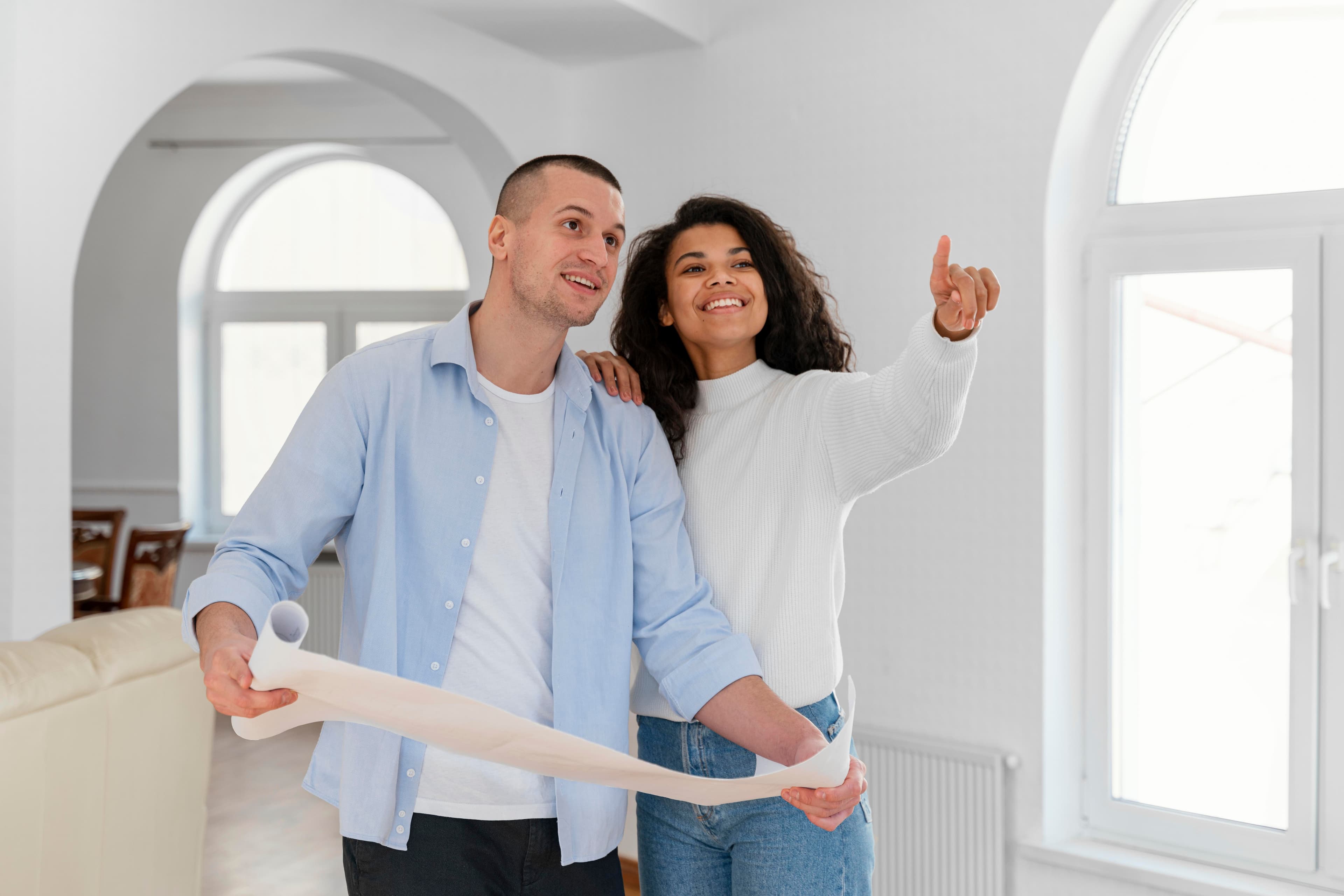 Una pareja recorriendo una vivienda con los planos en la mano